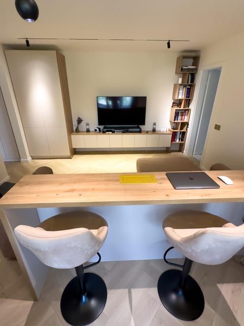 Living cu mobilier TV, bibliotecă, dulap înalt și blat de lucru cu două scaune